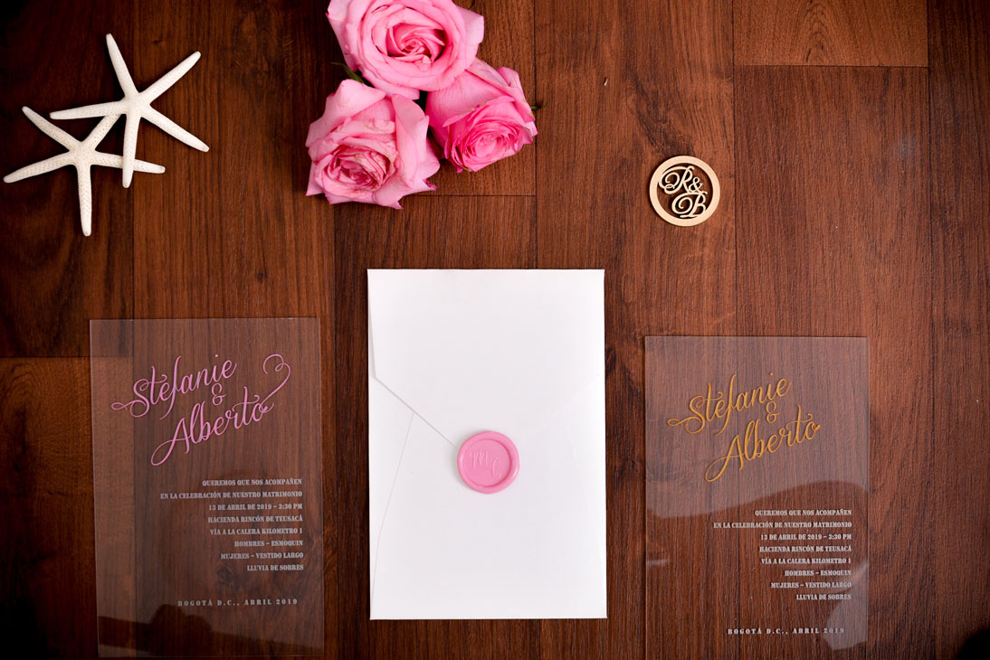 Invitación de matrimonio en acrílico con caligrafía dorada y fucsia