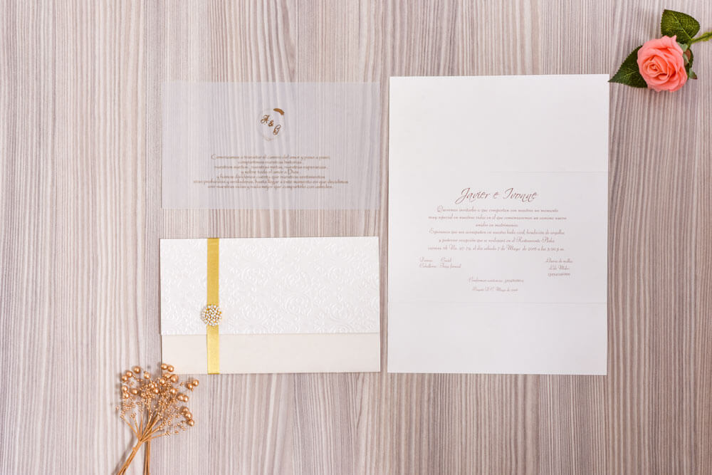 Invitación de matrimonio blanca con cinta dorada y broche de cristales