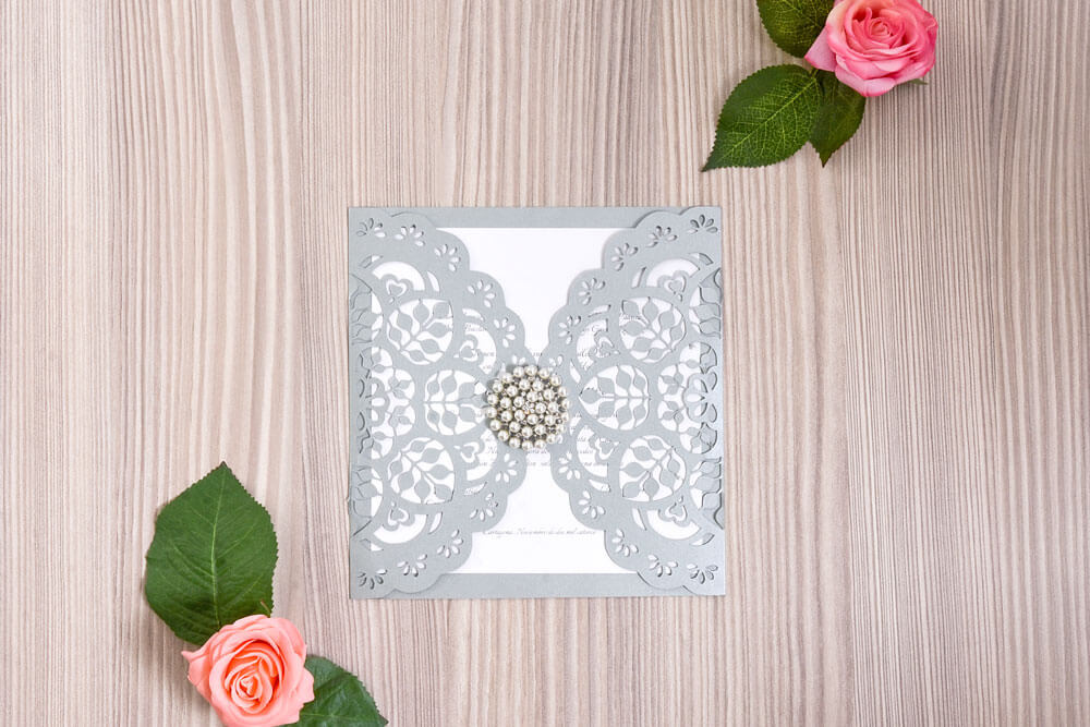 Invitación de matrimonio en encaje plateado con broche de perlas