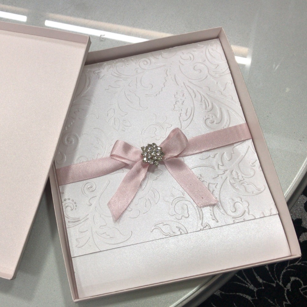 Invitación de primera comunión en caja rígida rosa con broche de cristales